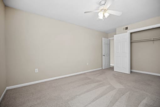 an empty living room with a closet and a ceiling fan