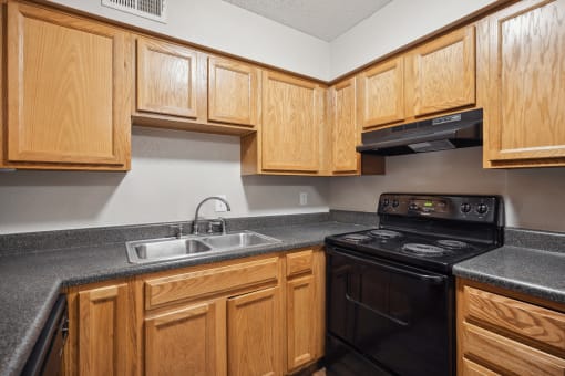an empty kitchen with wood cabinets and black appliances