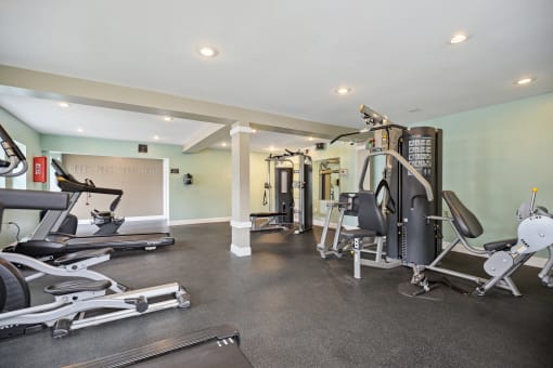 a gym with cardio equipment and weights on the floor