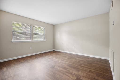 an empty living room with wood flooring and a window