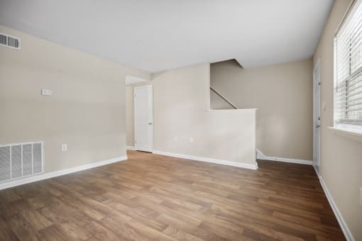 the living room of an apartment with wood flooring and a staircase