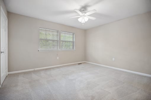 an empty living room with a ceiling fan and a window