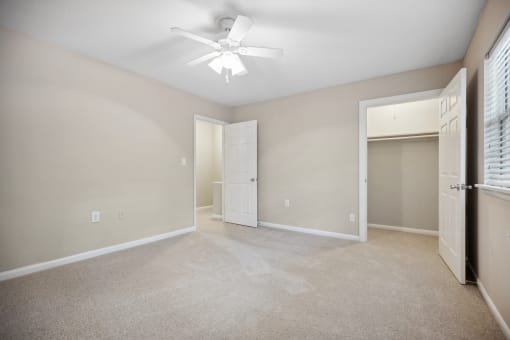 an empty living room with a ceiling fan and a closet