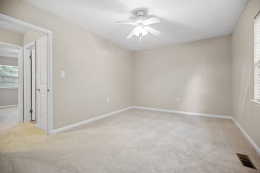 an empty room with a ceiling fan and a door to a closet