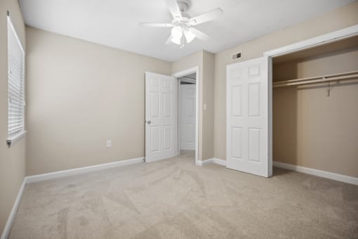 an empty bedroom with a closet and a ceiling fan