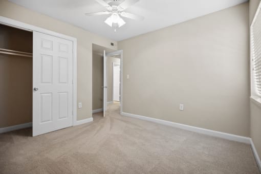 an empty living room with a white door and a ceiling fan