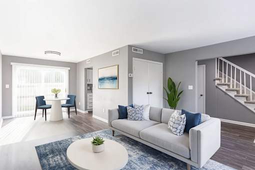 A living room with a white couch and a blue rug.