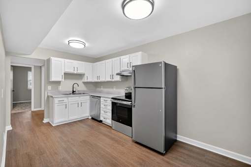 A kitchen with white cabinets and a black fridge.