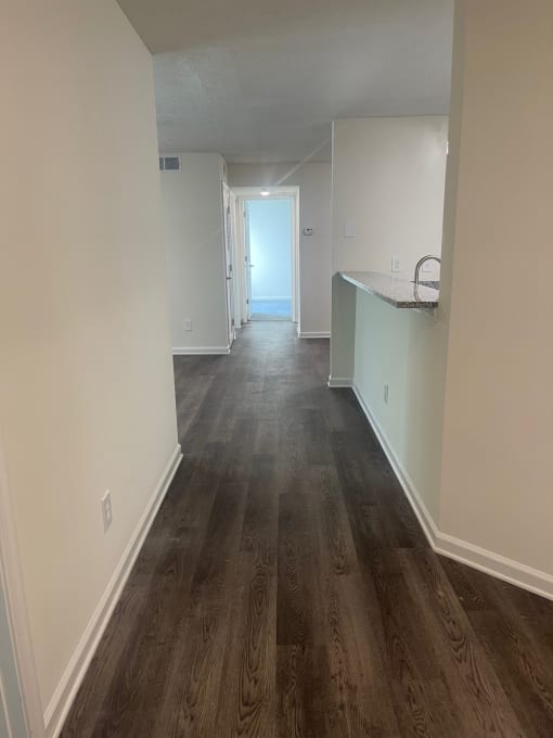 a living room and kitchen with wood floors and white walls