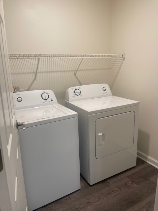 a washer and dryer in a room with a white wall and a closet