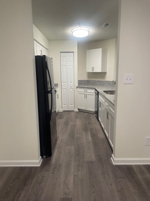a kitchen with white cabinets and a black refrigerator
