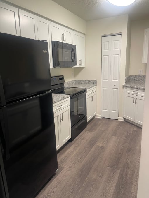 a kitchen with white cabinets and black appliances