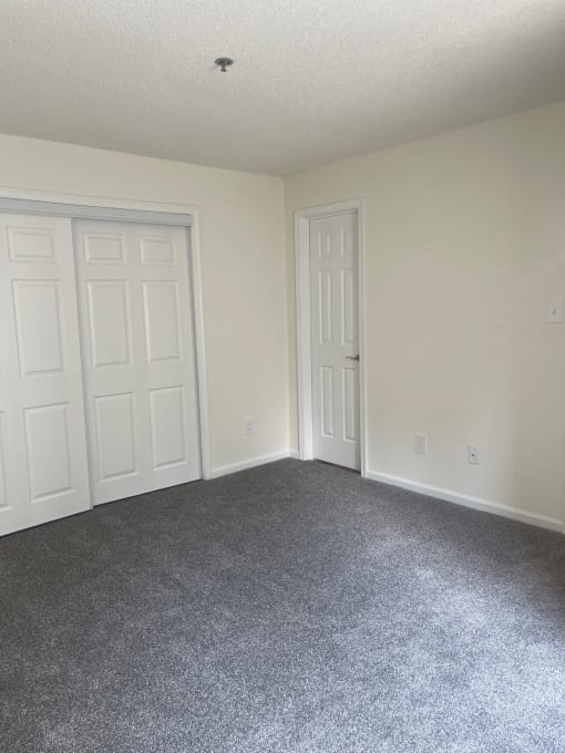 a bedroom with two doors and a carpeted floor