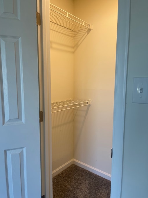 a walk in closet with an empty shelf and a door