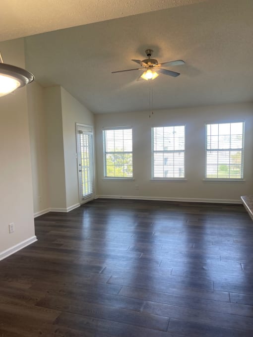 an empty living room with wood floors and a ceiling fan