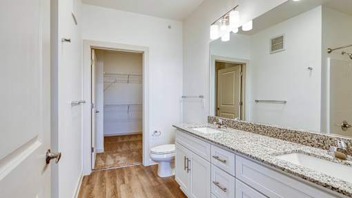 A bathroom with a toilet, sink, and mirror.