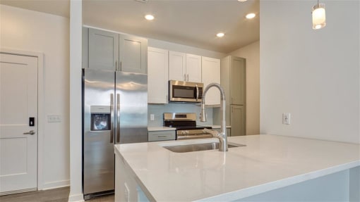 a kitchen with stainless steel appliances and white cabinets at The Port at East Beach Apartments and Marina, Virginia