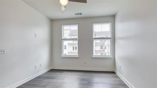 an empty living room with three windows and a ceiling fan at The Port at East Beach Apartments and Marina, Norkfolk, 23518