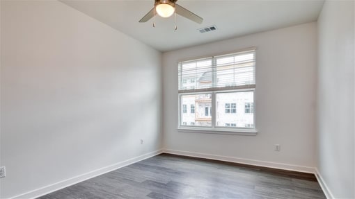 an empty bedroom with a ceiling fan and a window at The Port at East Beach Apartments and Marina, Virginia, 23518