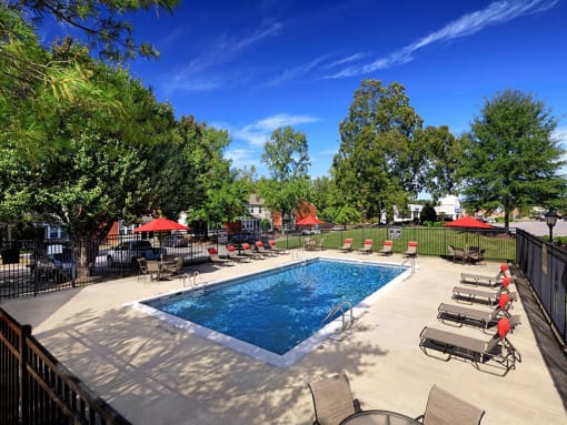 a swimming pool with chaise lounge chairs and umbrellas at Addison Crater Woods, Petersburg Virginia