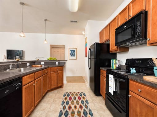 a kitchen with black appliances and wooden cabinets at Addison Crater Woods, Virginia, 23805