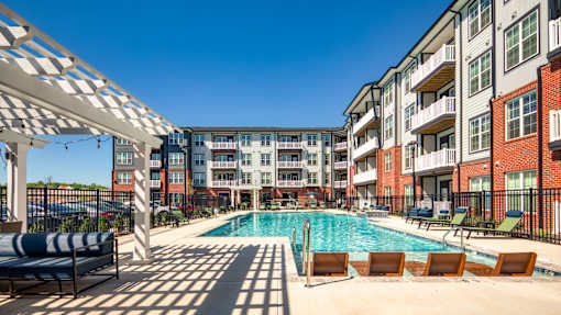 A pool area with sun loungers and a white canopy.