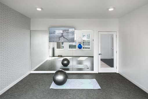 A room with a yoga mat and two exercise balls on the floor.