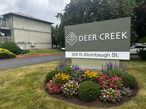 A sign for Deer Creek is in front of a building.
