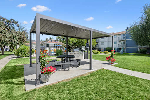 A picnic area with a table and chairs under a canopy.
