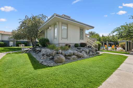 A house with a well-manicured lawn and a rock garden in front.