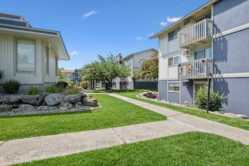 A sunny day in a residential area with apartment buildings and a well-kept lawn.