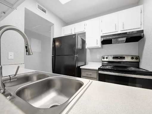 A kitchen with a black fridge and stove top oven.
