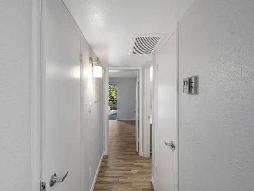 A long white hallway with doors on both sides and a light on the wall.