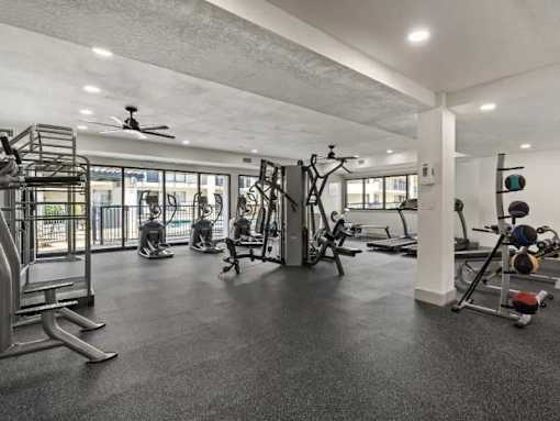 A spacious gym with a variety of equipment including treadmills, weights, and a fan.