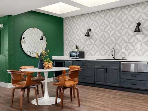 A kitchen with a green wall and a white table with chairs.