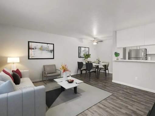 A living room with a grey sofa, a white coffee table, and a dining table with chairs.