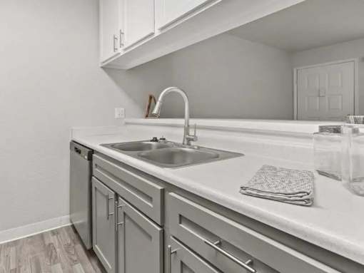 A modern kitchen with a white countertop and a stainless steel sink.