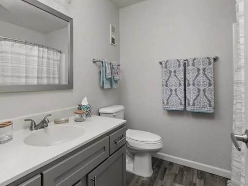 A bathroom with a toilet, sink, and towels.