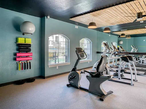 A gym with a row of treadmills and exercise equipment.