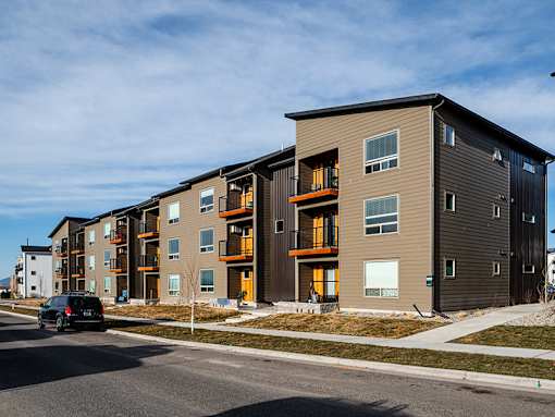 A modern apartment building with a car parked in front.