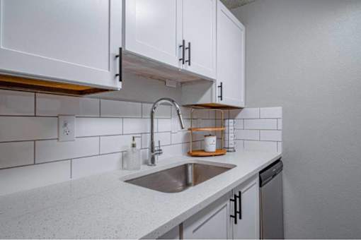 A kitchen with white cabinets and a stainless steel sink.