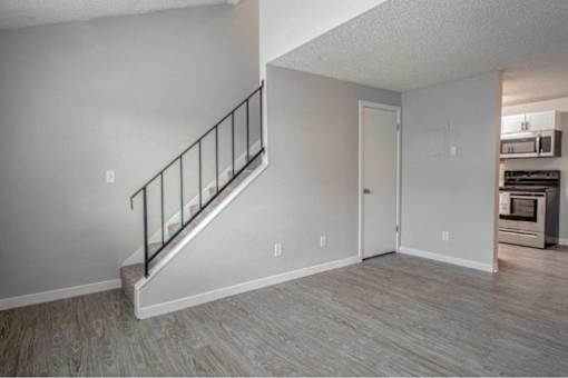 A room with a staircase and a door leading to a kitchen.