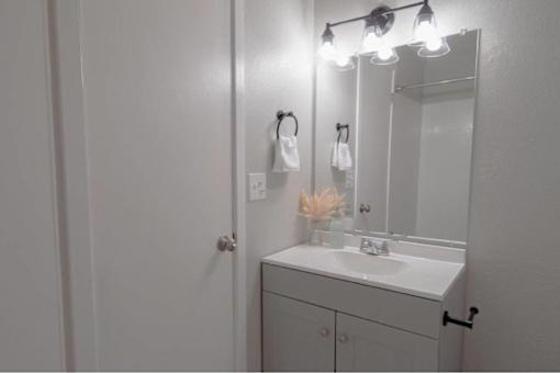 A bathroom with a white sink and a mirror with lights above it.