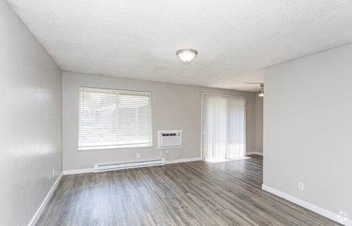 A room with a window and a wooden floor.