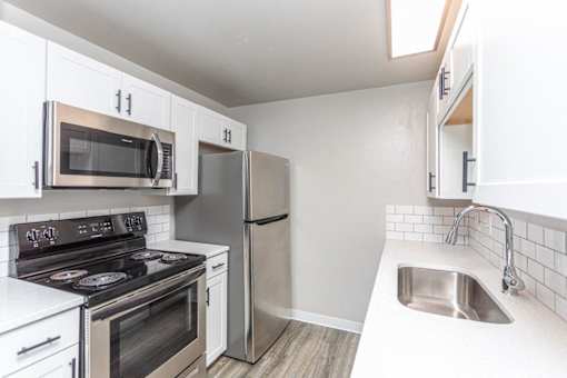 A kitchen with white cabinets and stainless steel appliances.