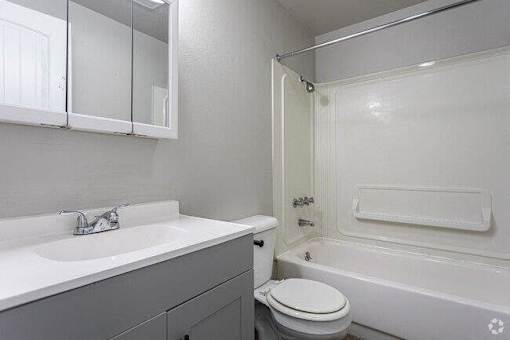 A white bathroom with a toilet, sink, and bathtub.