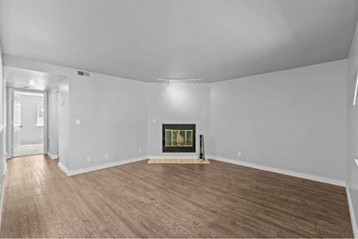 A room with a fireplace and wood flooring.