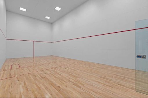 A squash court with a wooden floor and a red line down the middle.