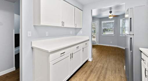 A kitchen with white cabinets and a wooden floor.