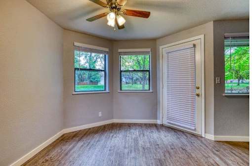A room with a ceiling fan and two windows.